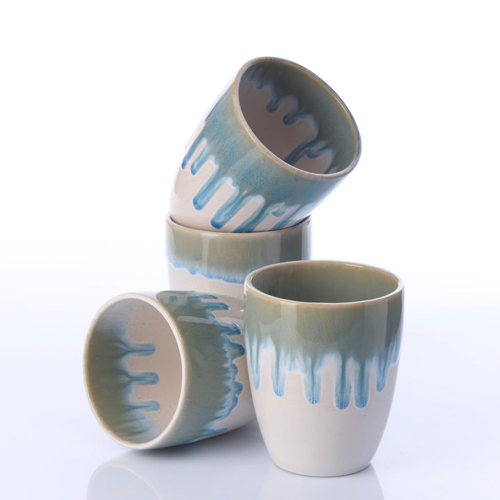 Vier weiße Keramikbecher EBB &amp; FLOW blau aus unterschiedlichen Perspektiven mit fließendem blauem Glasurverlauf